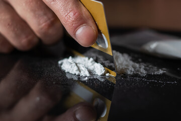 Fototapeta premium Man use credit card to make cocaine drug powder lines on black table