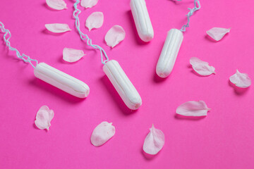Female tampons with with cherry petals on a pink background. Hygienic white tampon for women. Cotton swab.
