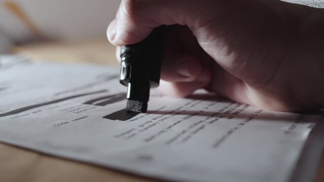 Hand uses black marker to redact censor or sanitize text before declassification. Man erases sensitive information from secret memo or document before publication or cover up by agency or government