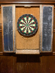 Well used dart board in a pub with chalk boards for keeping score.