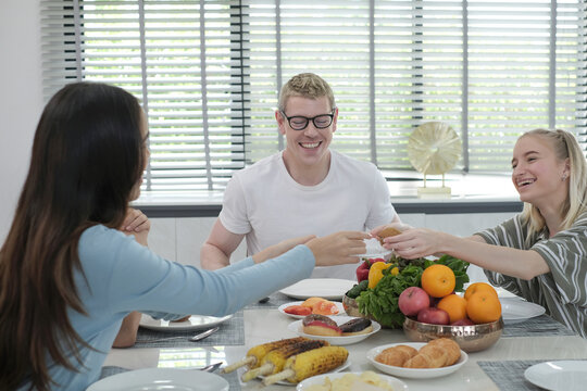 Happy multiracial family having dinner party In Kitchen Together - Group of friends dining at garden restaurant - Young people enjoying lunch break together - Food and beverage lifestyle concept.