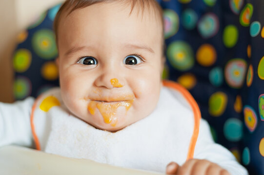 baby feeding process. the first baby food. Little baby don't like food. messy face. Meal time.