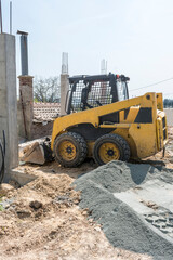 A small excavator in the park that prepares the asphalt pitch.