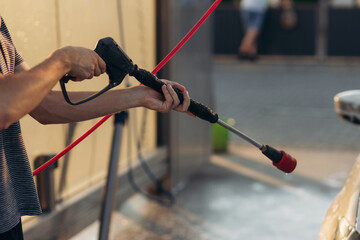 Close up car washing with high pressure car washer spray gun