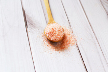 Fototapeta na wymiar Pink salt., Fine pink Himalayan salt in wooden spoon on a white wooden background.