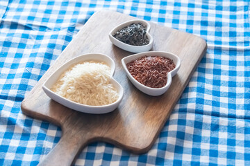 red, white and black rice on a wooden cutting board and checkered tablecloth