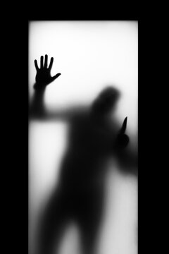 black silhouette on a light background, in the window with a knife, the horror of the appearance of a maniac in the window