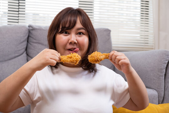 Young Asian oversize women gain weight while eating fried chicken, potato chips and French fried. Junk food that can cause obesity and unhealthy for human body.