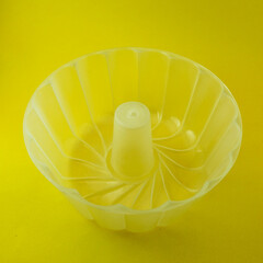 Plastic pudding mold in a yellow background