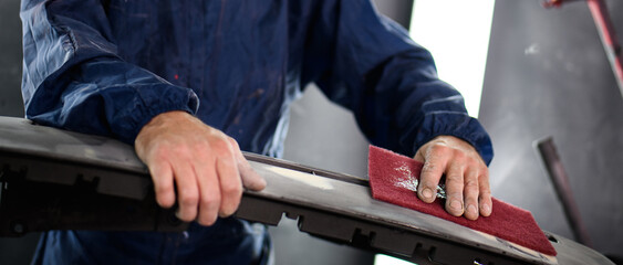 Banner shot of auto mechanic removing varnish from car part in auto service	