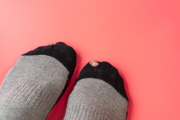 Socks with a hole on a light pink background.Broken sock with a hole.