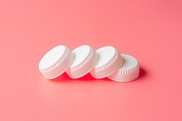 White bottles cap on light pink background.