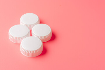 White bottles cap on light pink background.