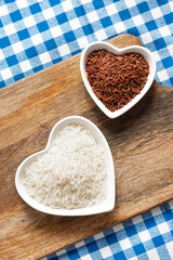white and red rice in a heart-shaped plate on a rustic background top view