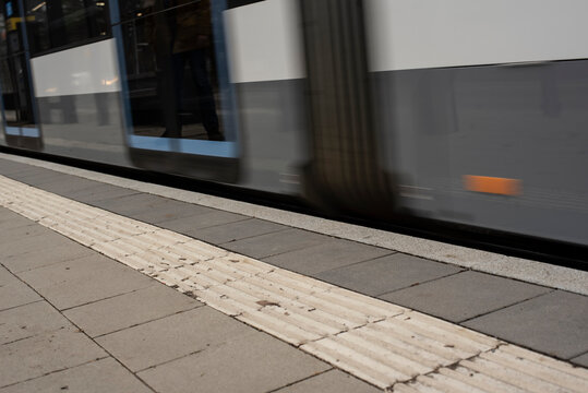 A Modern Streetcar Is Passing The Stop