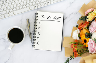 To do list text on note pad on top of office desk with bouquet of flower