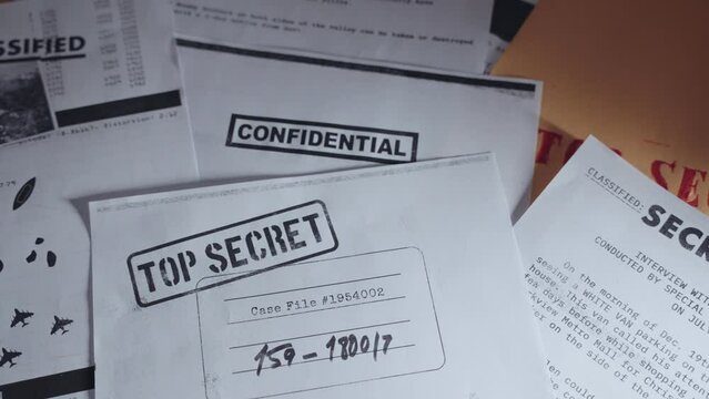 Hand setting down top secret paper on desk along side other classified documents. Person holding and then putting down photocopy of important confidential memo in a pile of secret papers