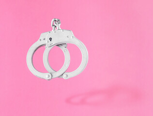 Locked or arrested handcuffs on isolated pastel pink background. The idea of victory, liberty, new...