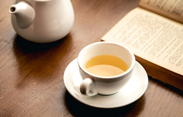 Close-up, a cup of tea and a book on a wooden table.