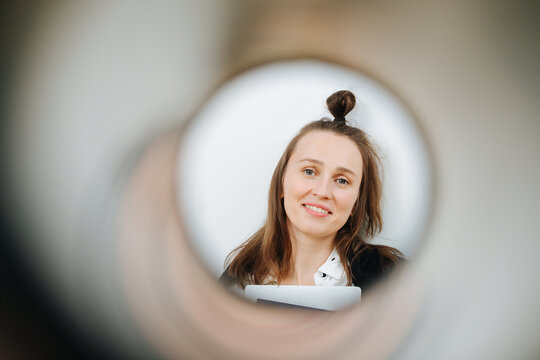 Portrait Of A Smiling 30 Year Old Woman Shot Through A Paper Roll