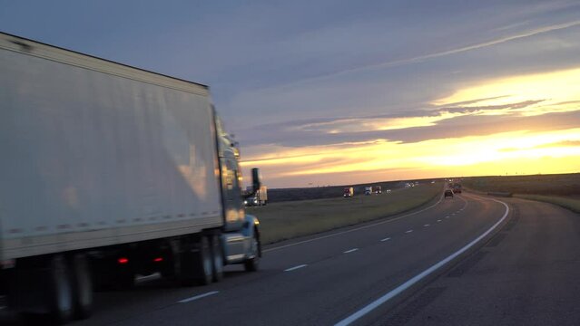 A cargo container semi-trailer carrying goods driving on an empty interstate highway through prairie fields in texas, america. Trailer carrying cargo on a sunny morning