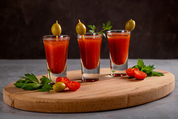 Shorts with alcoholic drink Bloody Mary on a wooden tray.