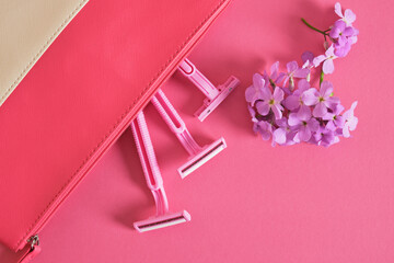 Safety razors and flowers on pink background, closeup