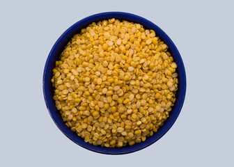 A bowl containing yellow lentil on a white background