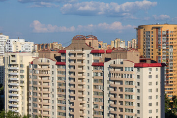 Urban landscape - modern multi-storey facades of houses on a sunny summer day and blue sky with clouds