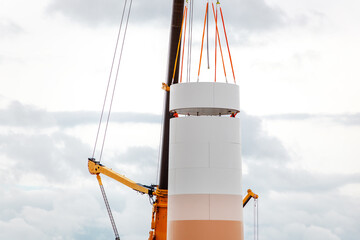 Building and assembling a construction windmill by crane. Farmland with construction work at the...