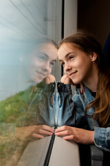 A young girl looks out the window of a train at the sea. Journey. Reflection. Vacation. Summer. Family vacation.