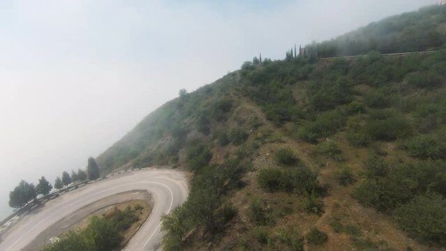 A long road on the mountain. Shot.A long track for cars is located on a high slope and thick fog is visible over the landscape.