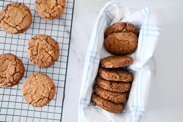Freshly baked healthy vegan cookie on a cooling rack stand on a table next to milk. View from