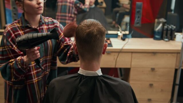 Barbershop: woman barber blow-dries a men's hair