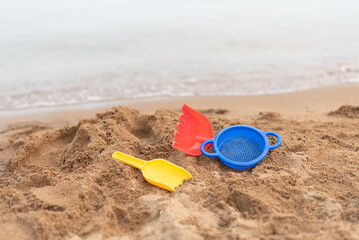 Children's beach toys on sandy beach with water in background