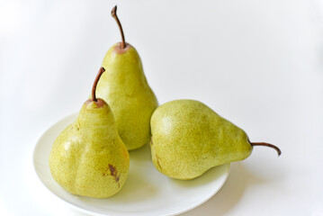 Green delicious pears on a white plate close-up