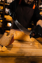 Cheese sommelier cutting limited gouda cheese with knife. Snack tasty piece of cheese for appetizer.