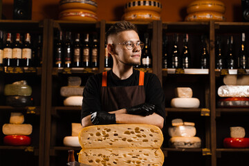Professional cheese sommelier in food shop. Worker of cheese store with limited maasdam natural aged.