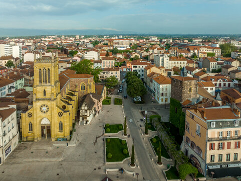 Aerial panoramic view of Roanne city center with yellow St Etienne church, medieval castle tower surrounded by modern city buildings