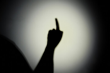 Shadow of a hand from the night light of a flashlight on a white wall. Dark silhouette of a man...