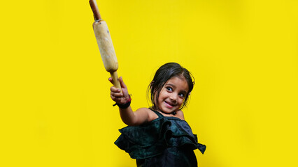 Angry frustrated little girl holding roll dough stick threatening someone