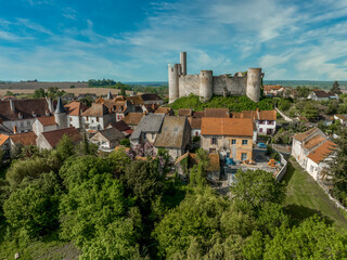 Aerial view of Billy castle above a sleepy medieval town in central France with semi-circular towers surrounding a courtyard cloudy blue sky