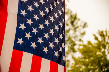 close-up of a flag of the USA flying on blurry nature background after rain