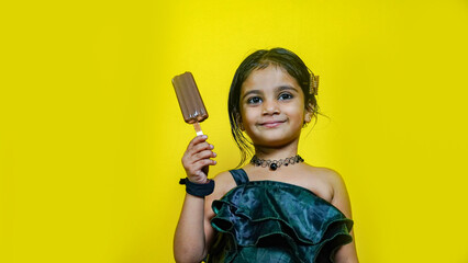 happy cute girl with chocolate ice-cream on yellow background