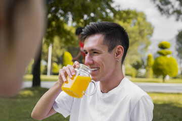 outdoor photo of young and modern man drinking natural orange juice in nature, sunlight photography