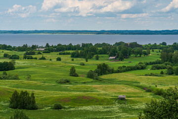 Fototapeta na wymiar A view from above to meadows, home, lake and horizon.