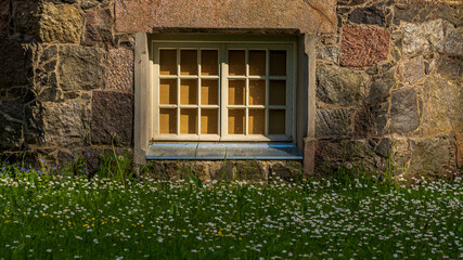 Stone wall and white window with white flower meadow