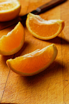 Close up view of three orange wedges on wooden cutting board