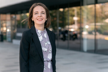 Young successful woman in black jacket on office center background. Smiling business woman.