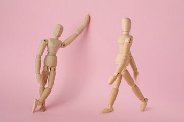 Wooden human models in different poses on pink background